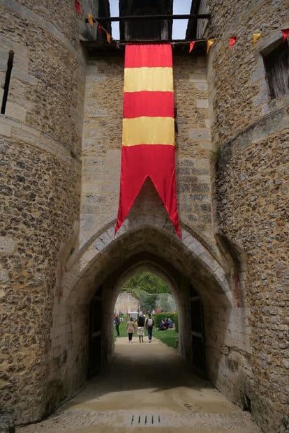 L'entrée d'un château médiéval avec un drapeau rouge et jaune.